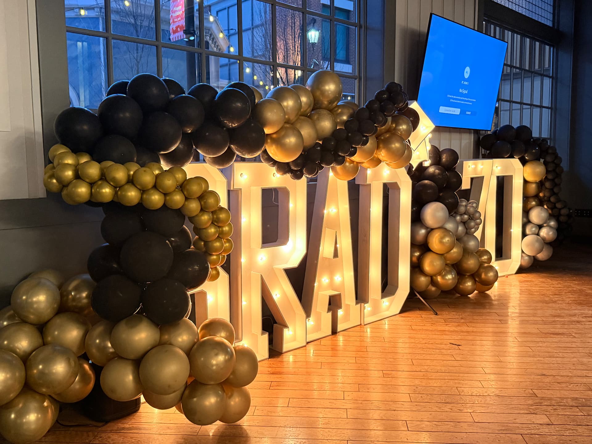 Lighted GRAD marquee letters wrapped in black, gold and silver balloon garland — Graduations by Good Time Mascots in Columbus, Ohio