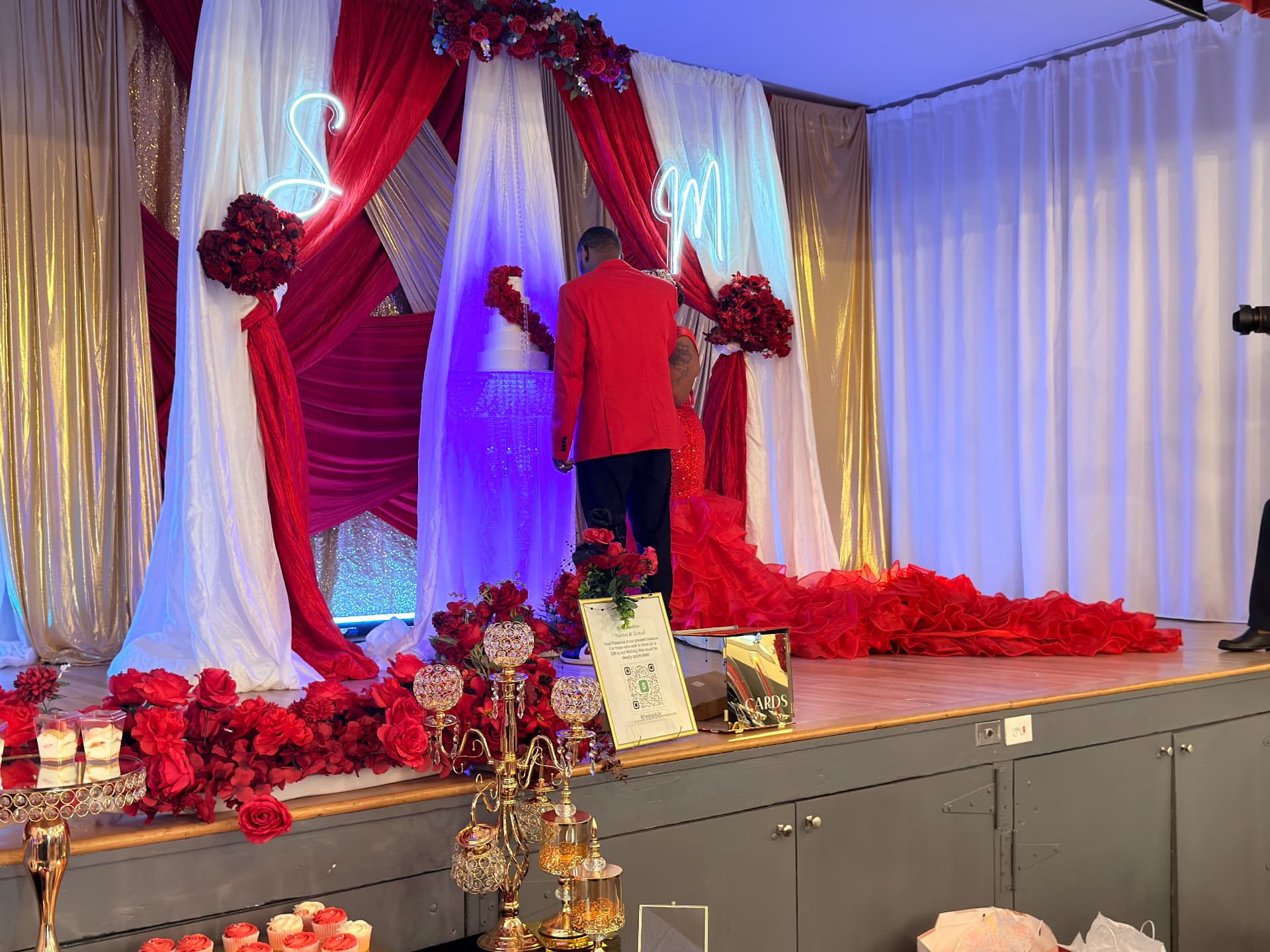 Cake-cutting stage with red roses, gold drape and neon monograms — Weddings by Good Time Mascots in Columbus, Ohio
